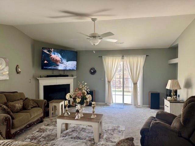 carpeted living room with visible vents, baseboards, a ceiling fan, vaulted ceiling, and a fireplace