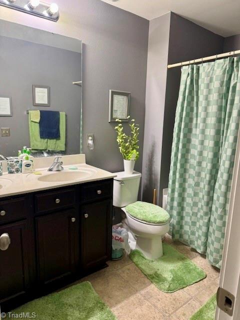 bathroom with double vanity, a shower with shower curtain, toilet, tile patterned flooring, and a sink