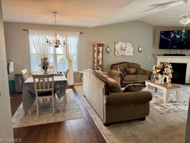 living room with lofted ceiling, a fireplace, wood finished floors, and ceiling fan with notable chandelier