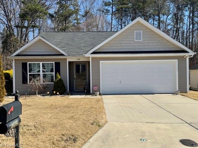 single story home featuring a garage, a front lawn, and concrete driveway