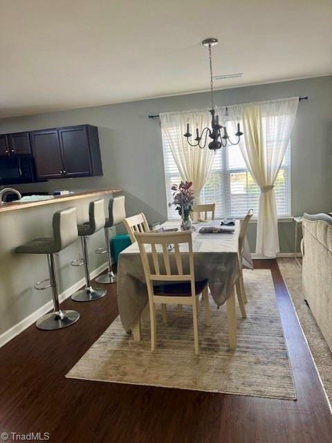 dining room featuring baseboards, dark wood finished floors, and a notable chandelier