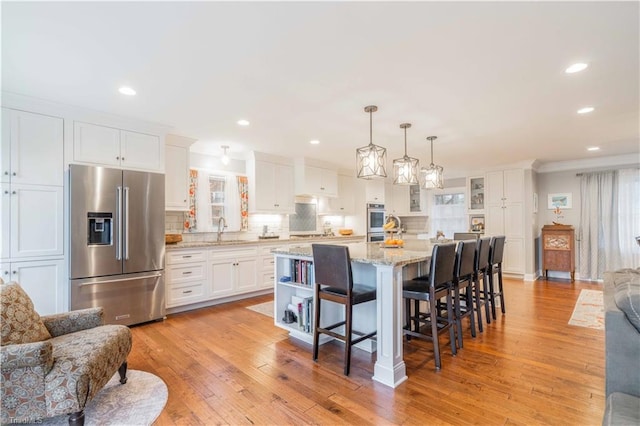 kitchen with light wood-style flooring, decorative backsplash, appliances with stainless steel finishes, white cabinets, and a sink