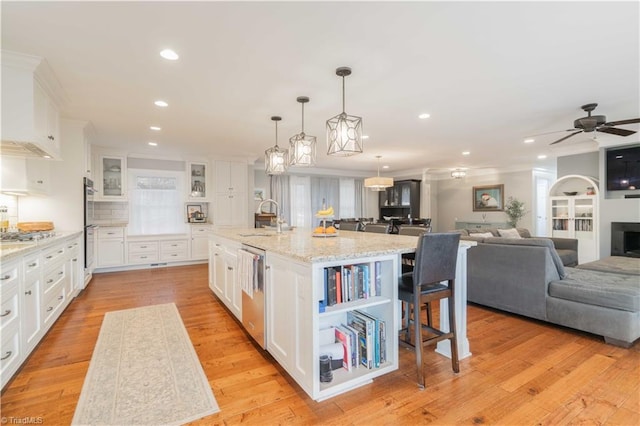 kitchen featuring light wood finished floors, a breakfast bar area, a sink, and white cabinets