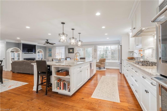 kitchen featuring stainless steel appliances, a fireplace, a sink, white cabinets, and open shelves