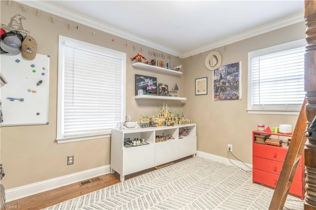 game room featuring visible vents, ornamental molding, baseboards, and wood finished floors