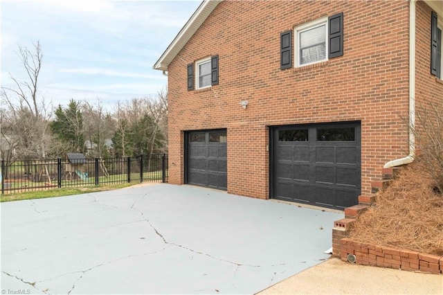 view of property exterior with a garage, driveway, and brick siding