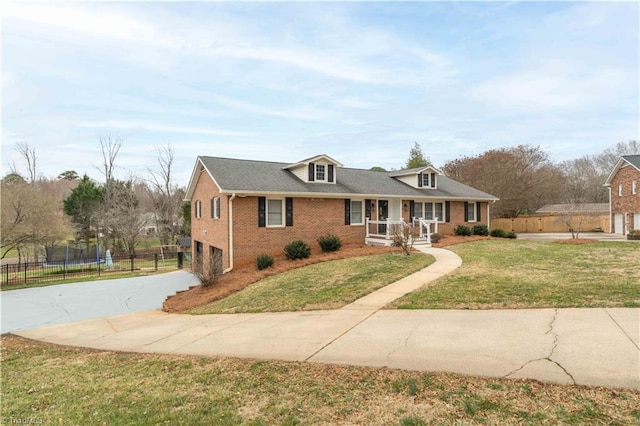 view of front of property with a trampoline, a porch, concrete driveway, fence, and a front lawn