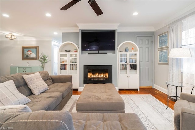 living room with recessed lighting, crown molding, a lit fireplace, and wood finished floors