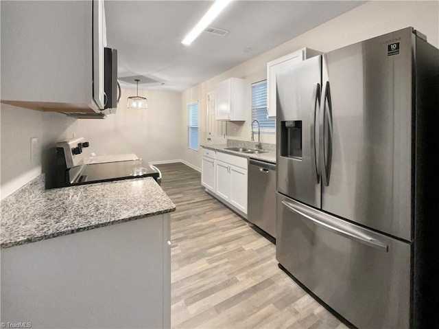 kitchen with light stone countertops, appliances with stainless steel finishes, sink, decorative light fixtures, and white cabinetry