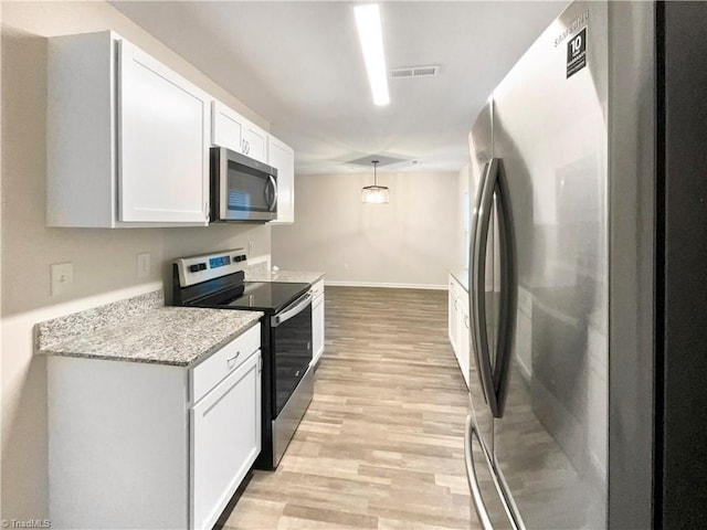 kitchen with light stone counters, white cabinetry, stainless steel appliances, and decorative light fixtures