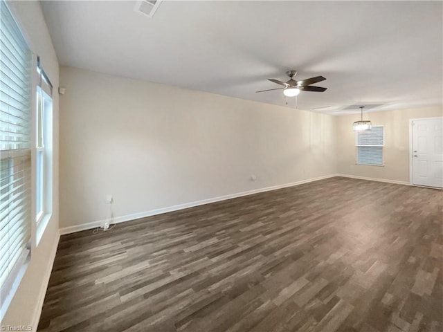 spare room with a wealth of natural light, ceiling fan, and dark wood-type flooring