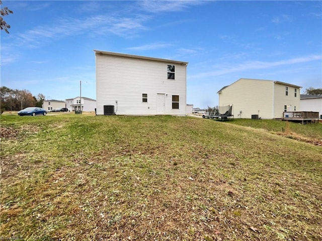 rear view of house with central AC and a yard