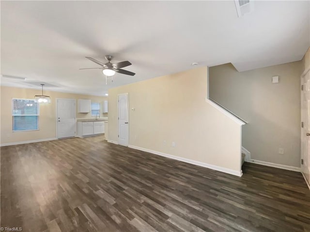 unfurnished living room featuring ceiling fan and dark wood-type flooring