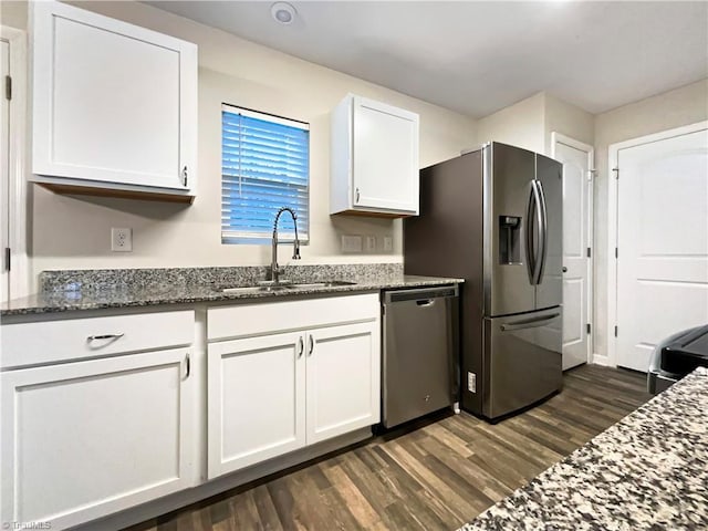 kitchen featuring sink, dark stone countertops, appliances with stainless steel finishes, dark hardwood / wood-style flooring, and white cabinetry