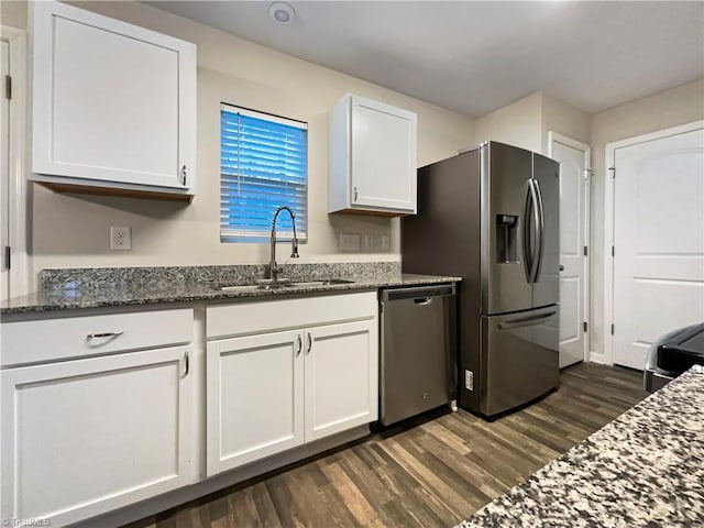 kitchen with dark wood-type flooring, white cabinets, sink, dark stone countertops, and stainless steel appliances