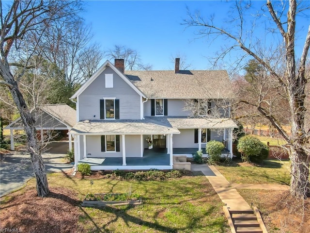 view of front of property featuring roof with shingles, covered porch, a front yard, and fence