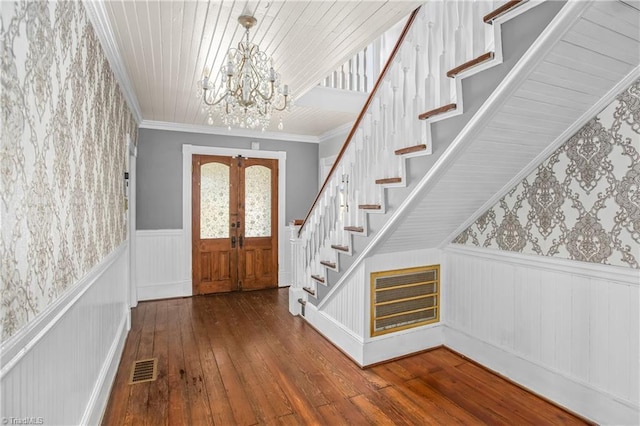 foyer entrance featuring stairway, visible vents, wallpapered walls, an inviting chandelier, and wainscoting