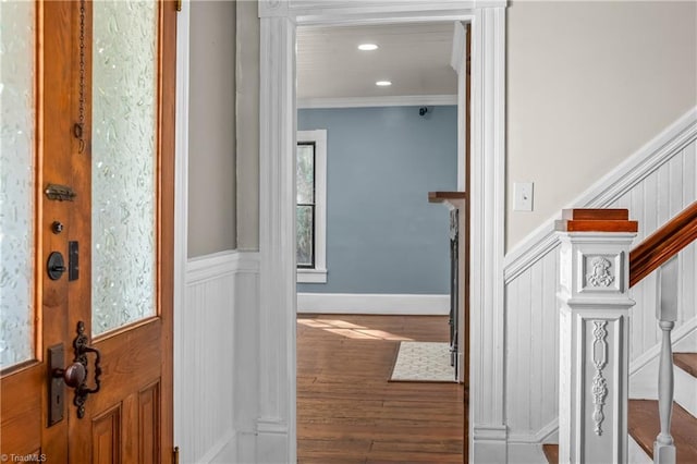 foyer entrance featuring stairway, wood finished floors, ornamental molding, and wainscoting