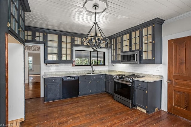 kitchen with a sink, a notable chandelier, appliances with stainless steel finishes, and dark wood-style floors