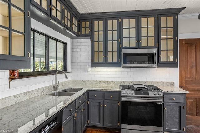 kitchen with backsplash, light stone countertops, stainless steel appliances, and a sink