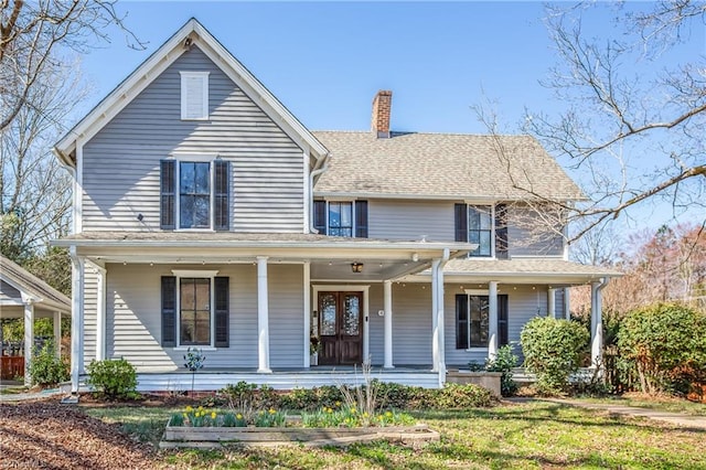 view of front of house featuring a front lawn, covered porch, and a chimney