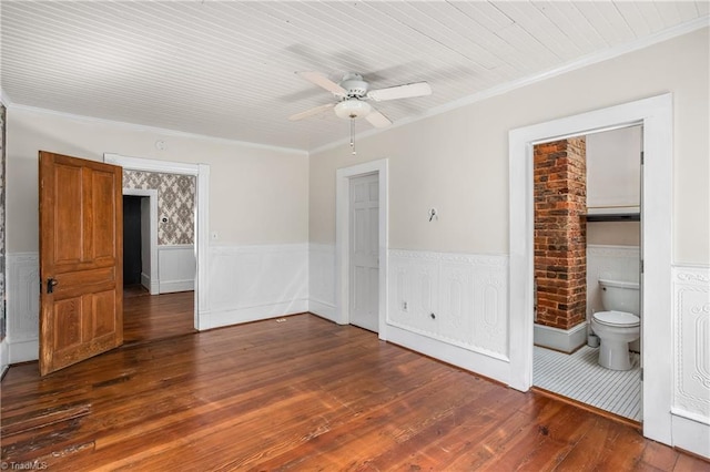 spare room with wainscoting, crown molding, dark wood-type flooring, and a ceiling fan