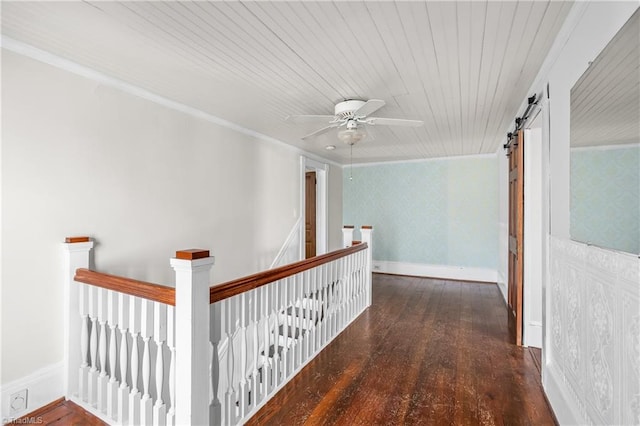 corridor with an upstairs landing, wallpapered walls, a barn door, and wood finished floors