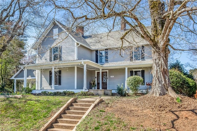 view of front facade with a front yard, a porch, and a chimney