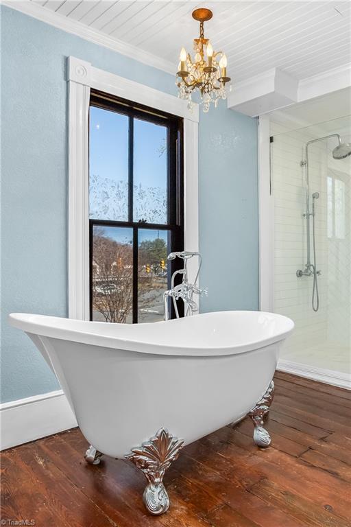 bathroom featuring hardwood / wood-style floors, baseboards, an inviting chandelier, a stall shower, and ornamental molding