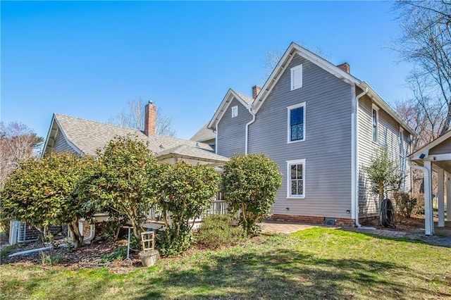 back of house featuring a patio area, a lawn, and a chimney