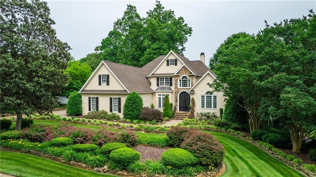 608 Greyrock Rd, Whitsett, NC 27377 - traditional-style house featuring a chimney, stucco siding, a front yard, and stone siding