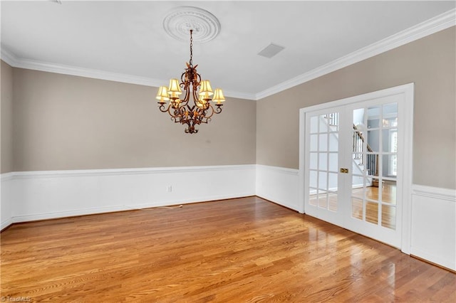 608 Greyrock Rd, Whitsett, NC 27377 - spare room with a chandelier, wood finished floors, ornamental molding, and wainscoting