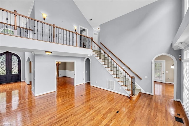 608 Greyrock Rd, Whitsett, NC 27377 - unfurnished living room featuring arched walkways, high vaulted ceiling, wood finished floors, stairway, and french doors