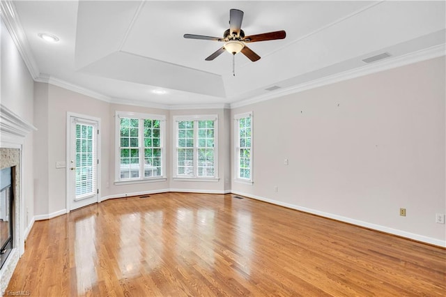 608 Greyrock Rd, Whitsett, NC 27377 - unfurnished living room featuring light wood-style floors, a high end fireplace, a tray ceiling, a ceiling fan, and baseboards