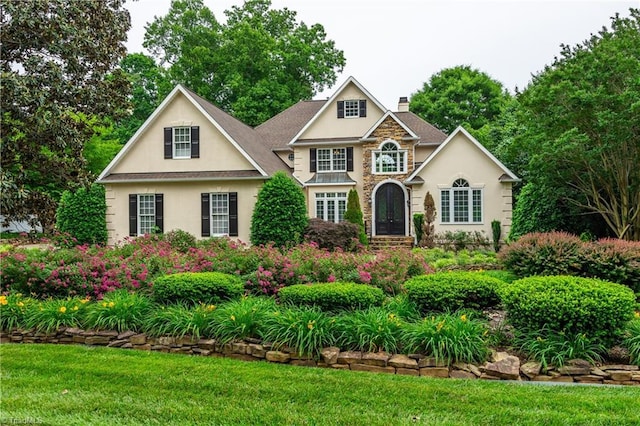 608 Greyrock Rd, Whitsett, NC 27377 - view of front facade featuring a chimney, stucco siding, stone siding, and a front lawn