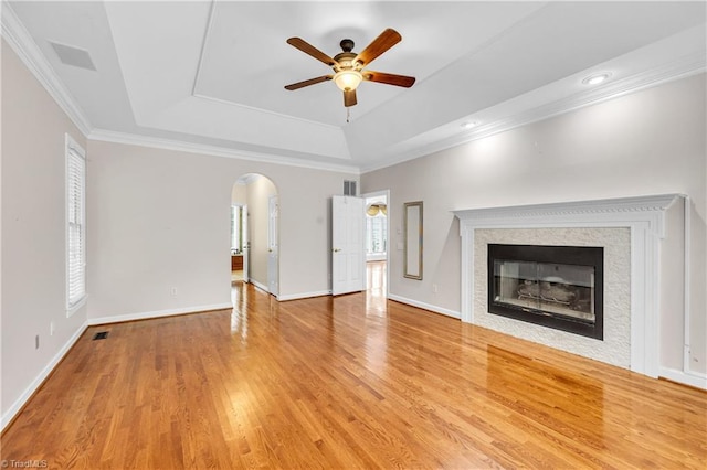 608 Greyrock Rd, Whitsett, NC 27377 - unfurnished living room with a raised ceiling, arched walkways, ceiling fan, ornamental molding, and a glass covered fireplace