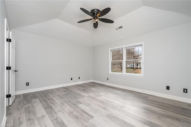 spare room with a raised ceiling, ceiling fan, light hardwood / wood-style flooring, and vaulted ceiling