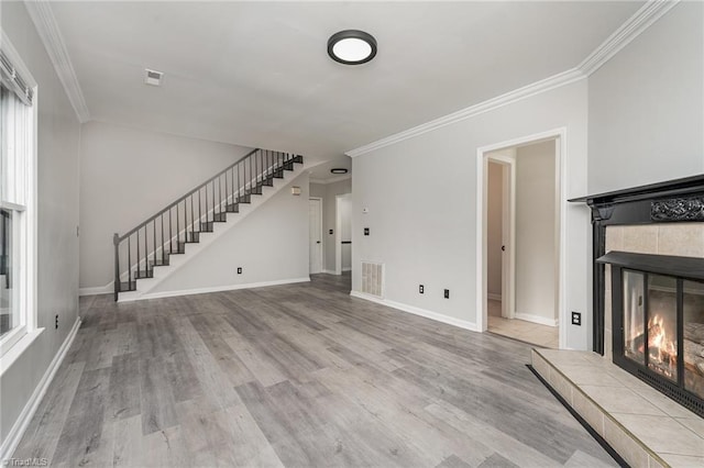 unfurnished living room featuring ornamental molding, a tile fireplace, and light hardwood / wood-style flooring