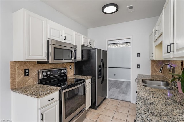 kitchen with white cabinets, stainless steel appliances, light stone countertops, and sink