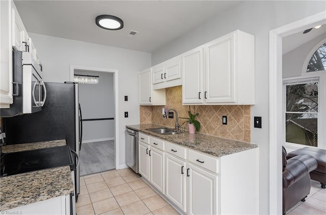 kitchen featuring appliances with stainless steel finishes, white cabinetry, dark stone counters, and sink