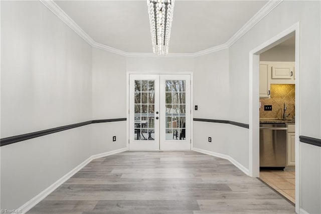 unfurnished dining area featuring french doors, ornamental molding, sink, light hardwood / wood-style flooring, and an inviting chandelier