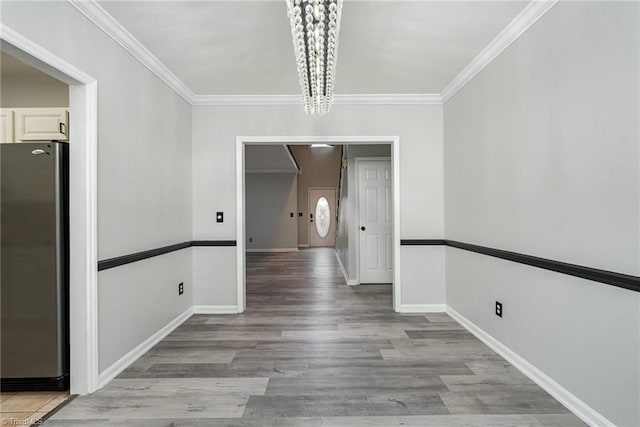 unfurnished dining area with a notable chandelier, crown molding, and light hardwood / wood-style flooring