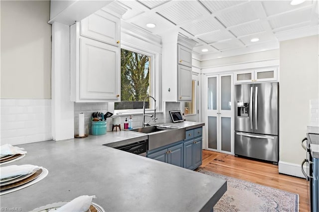 kitchen with blue cabinetry, stainless steel fridge with ice dispenser, white cabinetry, and sink