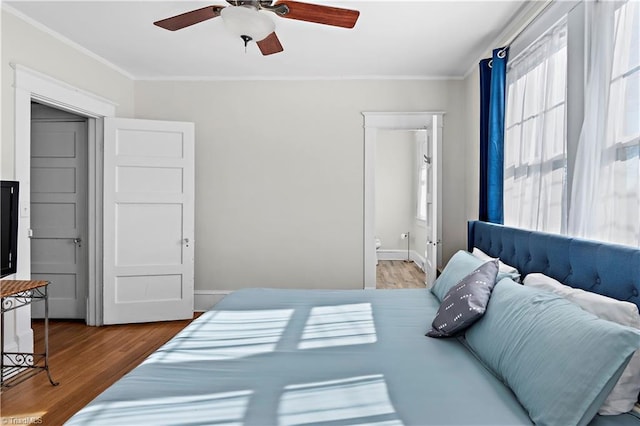 bedroom with connected bathroom, hardwood / wood-style flooring, ceiling fan, and crown molding