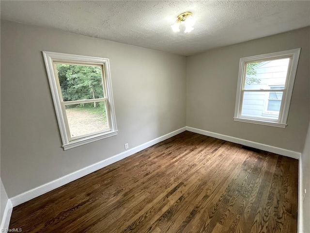 spare room featuring dark wood-type flooring, a healthy amount of sunlight, and a textured ceiling