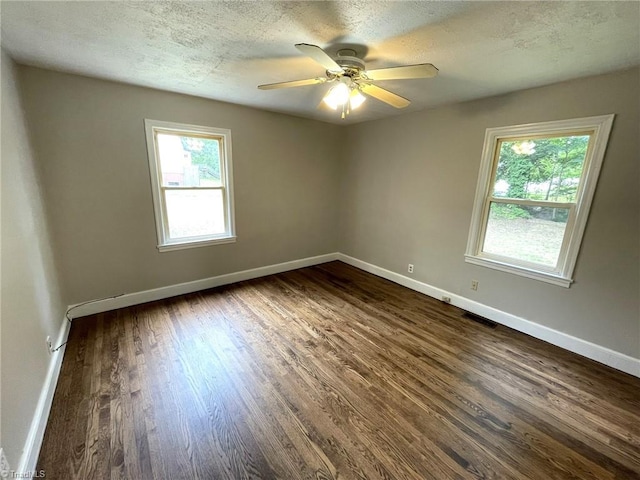 empty room featuring a textured ceiling, dark hardwood / wood-style flooring, ceiling fan, and a healthy amount of sunlight