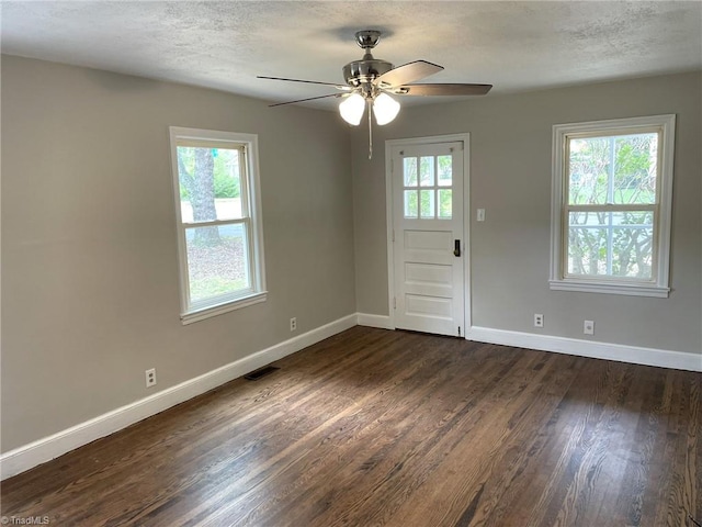 empty room with dark hardwood / wood-style floors, ceiling fan, and a healthy amount of sunlight