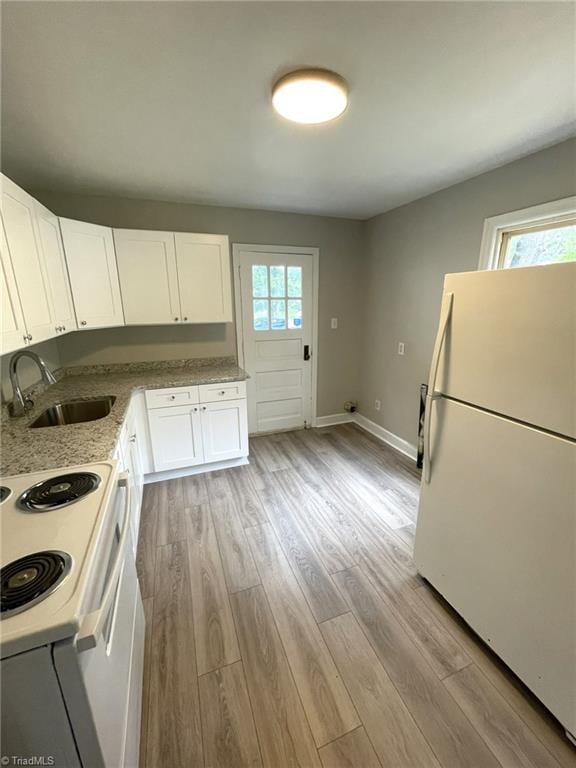 kitchen featuring white appliances, sink, white cabinets, and light hardwood / wood-style floors