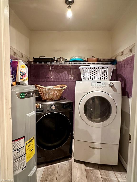 laundry room with electric water heater, light hardwood / wood-style flooring, and washer and dryer