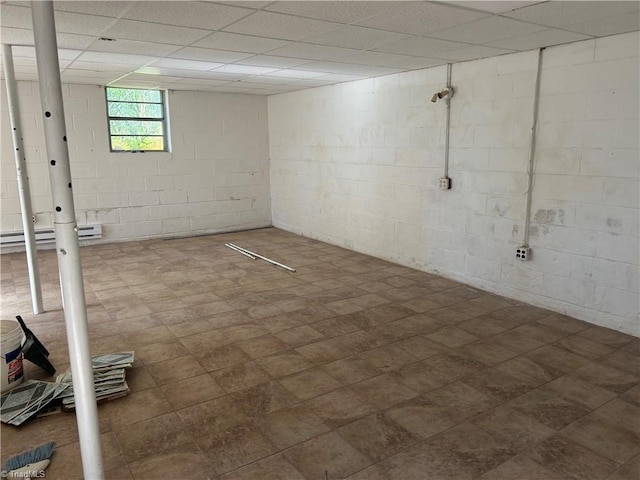 basement with a paneled ceiling and a baseboard radiator